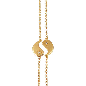 Gold necklace with a yin yang pendant on a white background