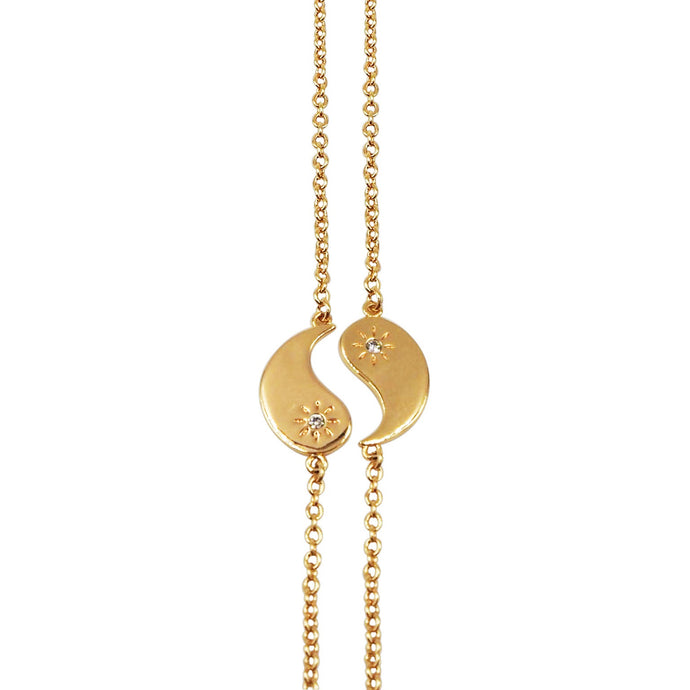 Gold necklace with a yin yang pendant on a white background