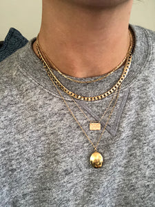 Yantra necklace layered with other gold necklaces